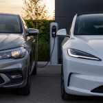 Carro convencional e veículo elétrico estacionados lado a lado em área externa