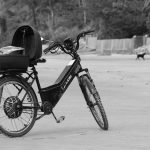 Bicicleta elétrica apoiada na areia da praia de Guaratuba, no Paraná, em imagem em preto e branco.