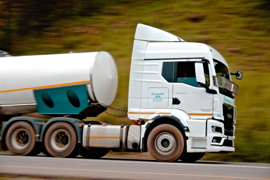 Caminhão-tanque branco em movimento em uma rodovia, com efeito de velocidade.