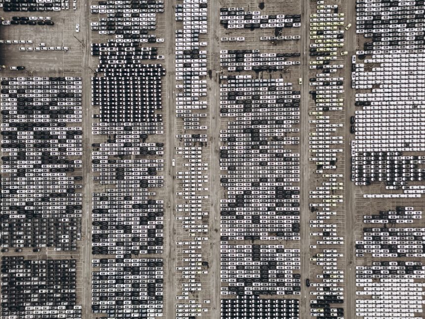 Vista aérea de um amplo pátio no Brasil com milhares de veículos estacionados.