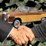 Comprador e vendedor apertam as mãos ao lado de um carro durante uma negociação de venda.